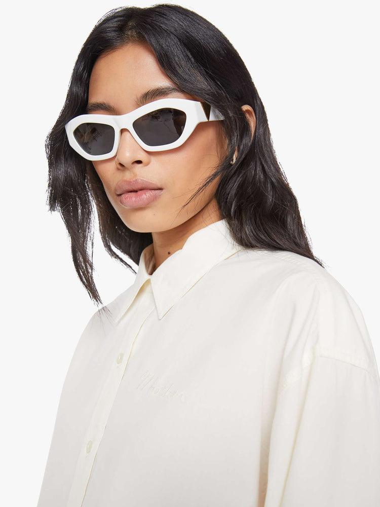 Close up view of a woman in an antique white with a chain stitched MOTHER on front and back oversized button-up blouse with drop shoulders and a curved hem.