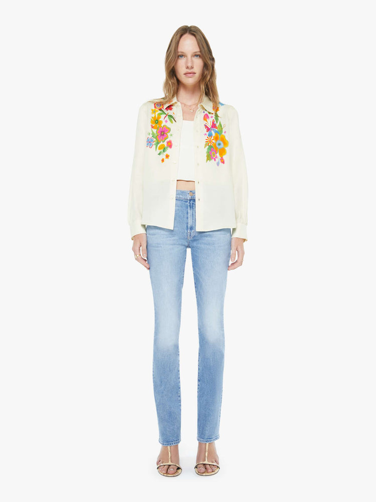 Full body  view of a woman in an off white with colored flowers collared button-up with long gathered sleeves and a cropped, curved hem.
