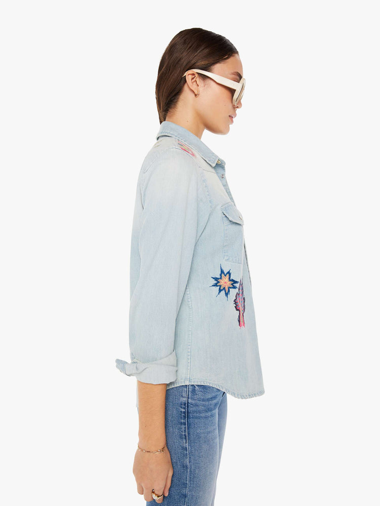 Side view of a womens denim shirt featuring embroidered details.