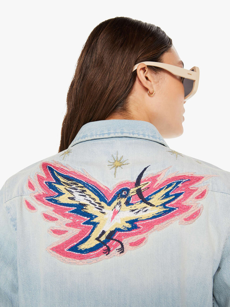 Back close up view of a womens denim shirt featuring embroidered details.