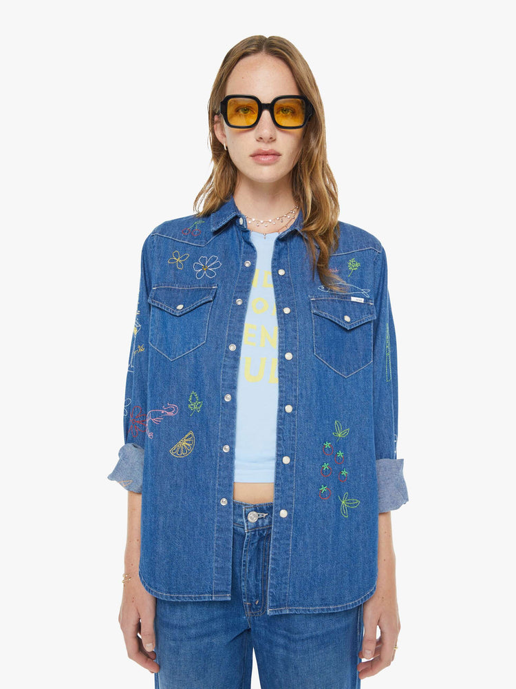 Front view of a woman in a classic blue denim button-up with front patch pockets and a curved hem.