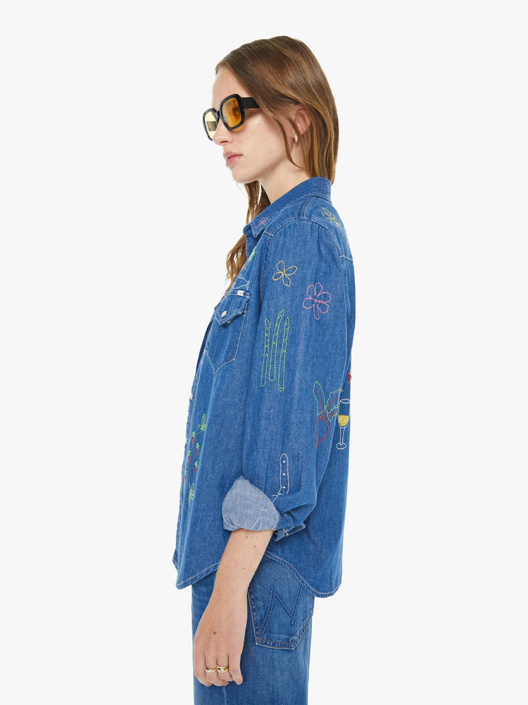 Side view of a woman in a classic blue denim button-up with front patch pockets and a curved hem.