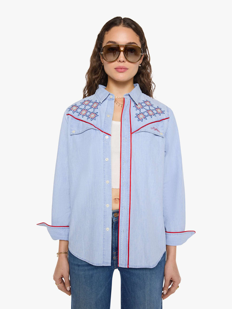 Front view of a woman in a light blue classic button-up shirt with a curved hem and a loose fit.