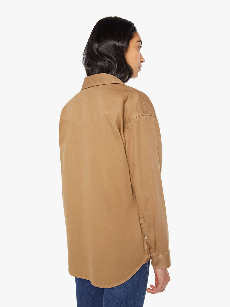 Back view of a woman in khaki denim button-up with drop shoulders, front patch pockets, a Western-inspired yoke and a curved hem.