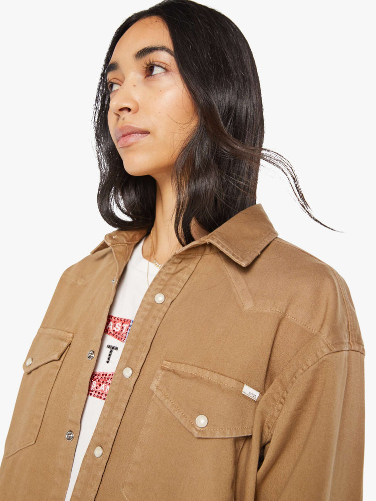 Close up view of a woman in khaki denim button-up with drop shoulders, front patch pockets, a Western-inspired yoke and a curved hem.