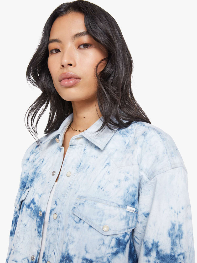 Close up view of a bleached tie die oversized button-up with drop shoulders, front patch pockets, a Western-inspired yoke and a curved hem.