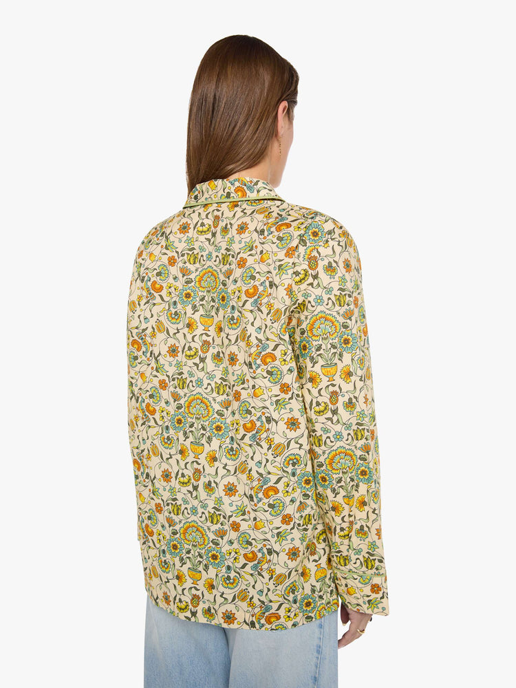 Back view of woman in a collared, long-sleeve button-up blouse with a patch pocket and boxy fit.