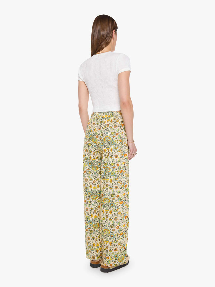 Back pant view of woman in two-piece pajama set includes a collared, long-sleeve button-up blouse with a patch pocket and boxy fit, and loose, wide-leg pants with slit pockets and an elastic hem.