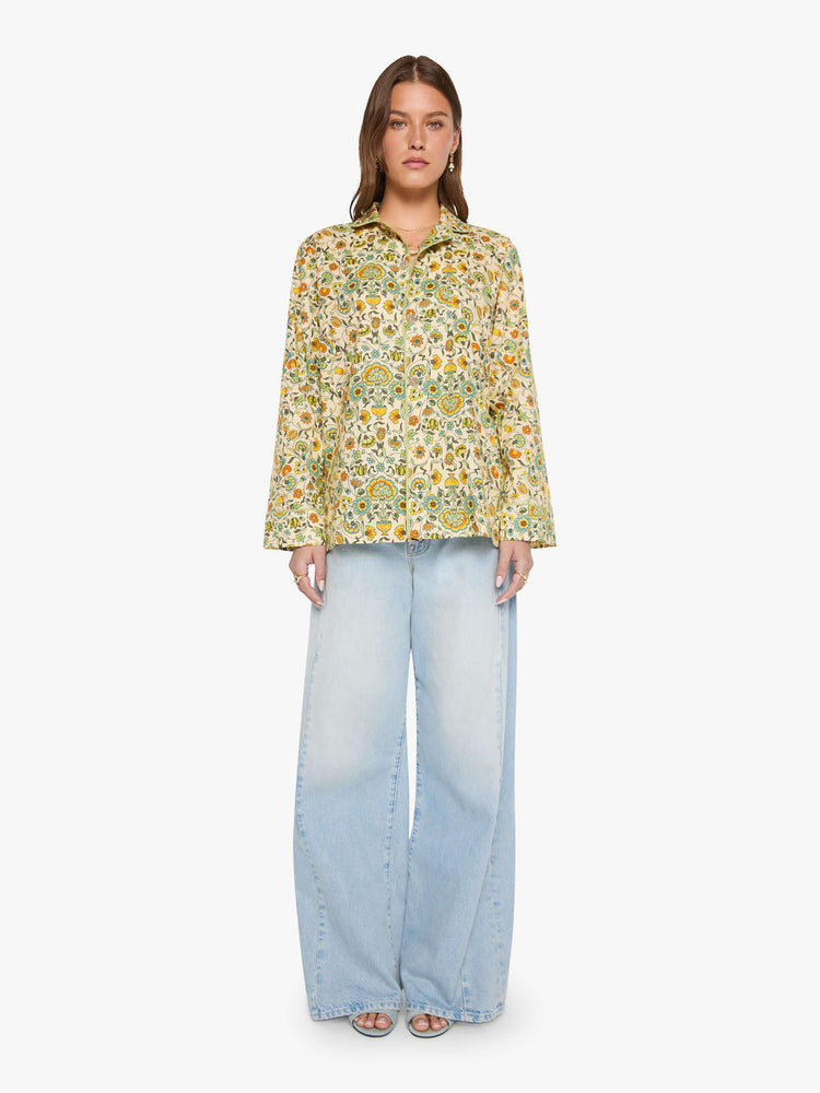 Full view of woman in a collared, long-sleeve button-up blouse with a patch pocket and boxy fit.