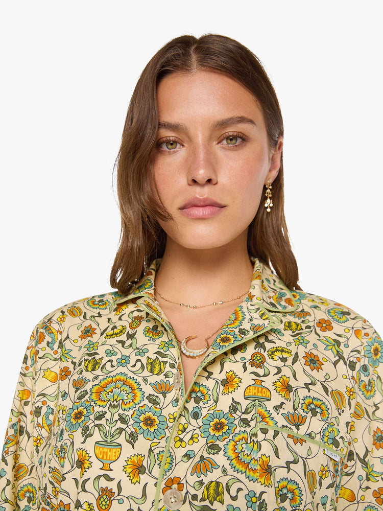 Close up face view of woman in two-piece pajama set includes a collared, long-sleeve button-up blouse with a patch pocket and boxy fit, and loose, wide-leg pants with slit pockets and an elastic hem.