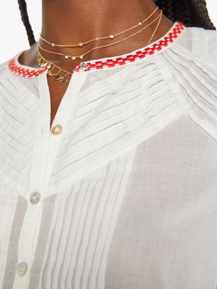 Swatch view of a woman white blouse blouse with a crewneck, 3/4-length balloon sleeves, pleated details, buttons down the front and a slightly shrunken fit in white with red trim around the neck and sleeves.