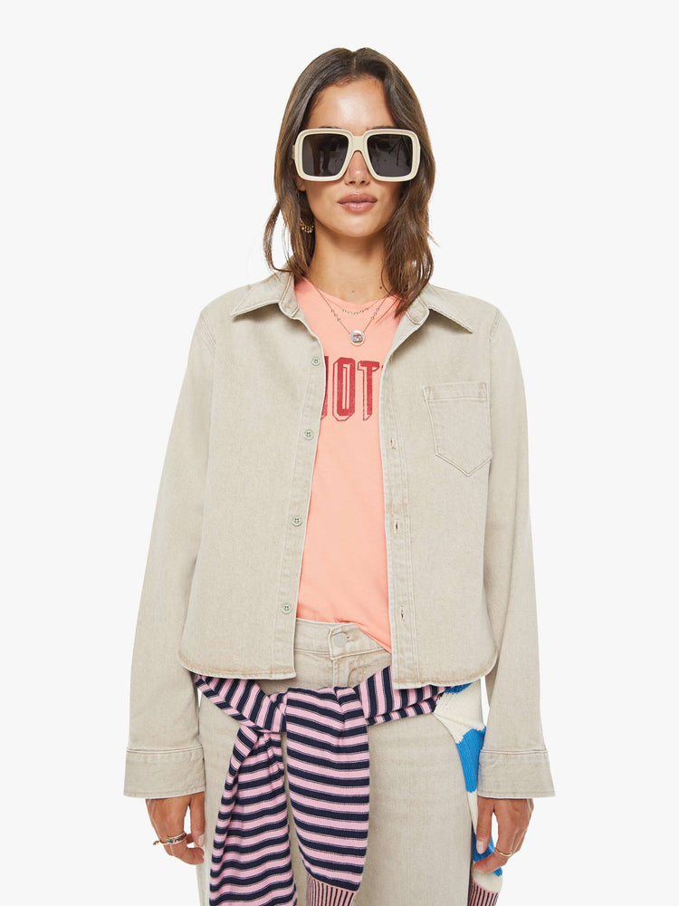 Front view of a woman in faded khaki  button-up denim top with a front patch pocket and a curved, cropped hem. 