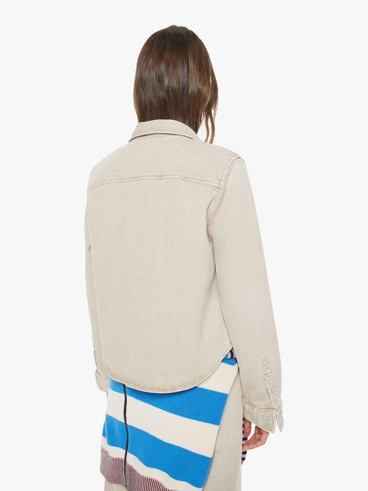 Back view of a woman in faded khaki  button-up denim top with a front patch pocket and a curved, cropped hem.