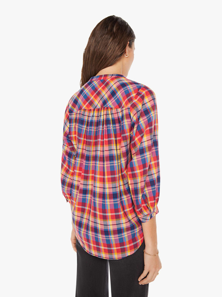 Back view of a woman hot pink, yellow, and blue plaid lightweight blouse with a buttoned V-neck, 3/4-length balloon sleeves, a curved hem and ruffles throughout for a loose, flowy fit.