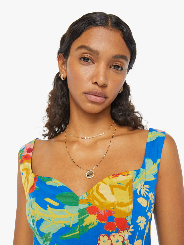 Detailed view of a woman in a blue sleeveless corset with an oversized tropical floral print, a sweetheart neckline, seamed details, a smocked, elastic back panel and a cropped, narrow fit. 