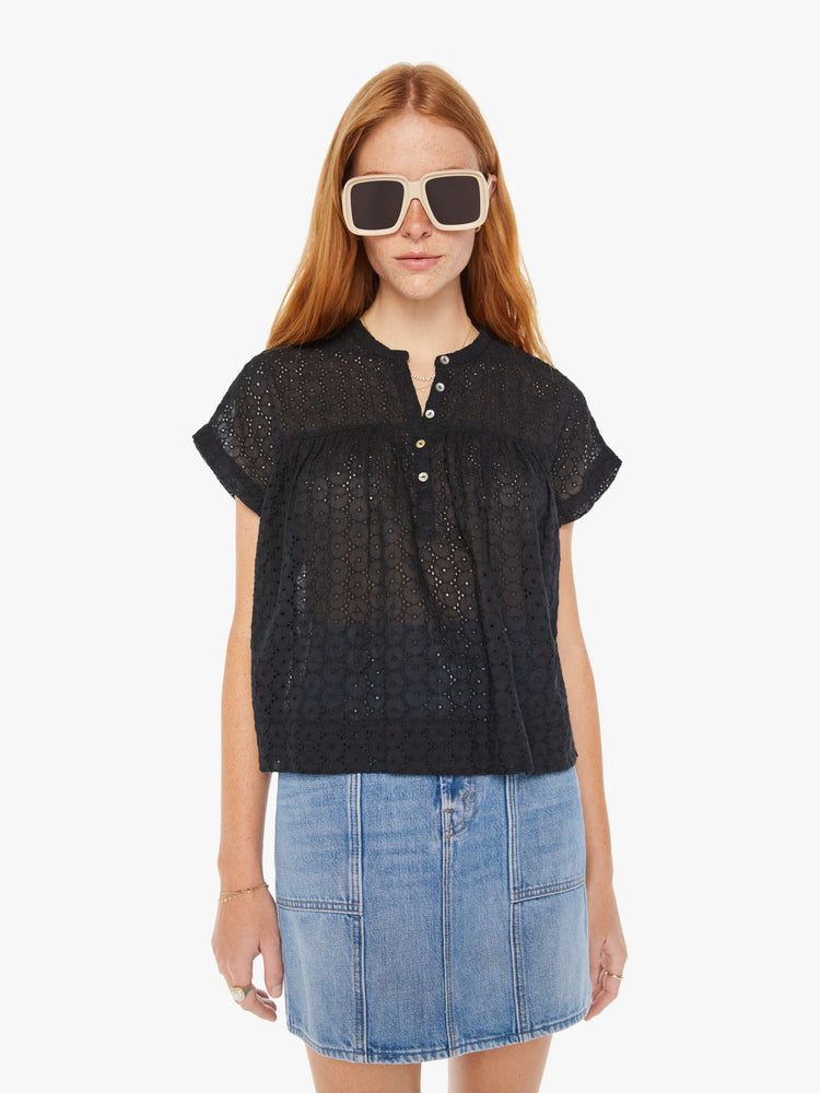 Front view of a woman black lightweight blouse with a buttoned V-neck, short boxy sleeves and ruffles across the chest for a loose, flowy fit.