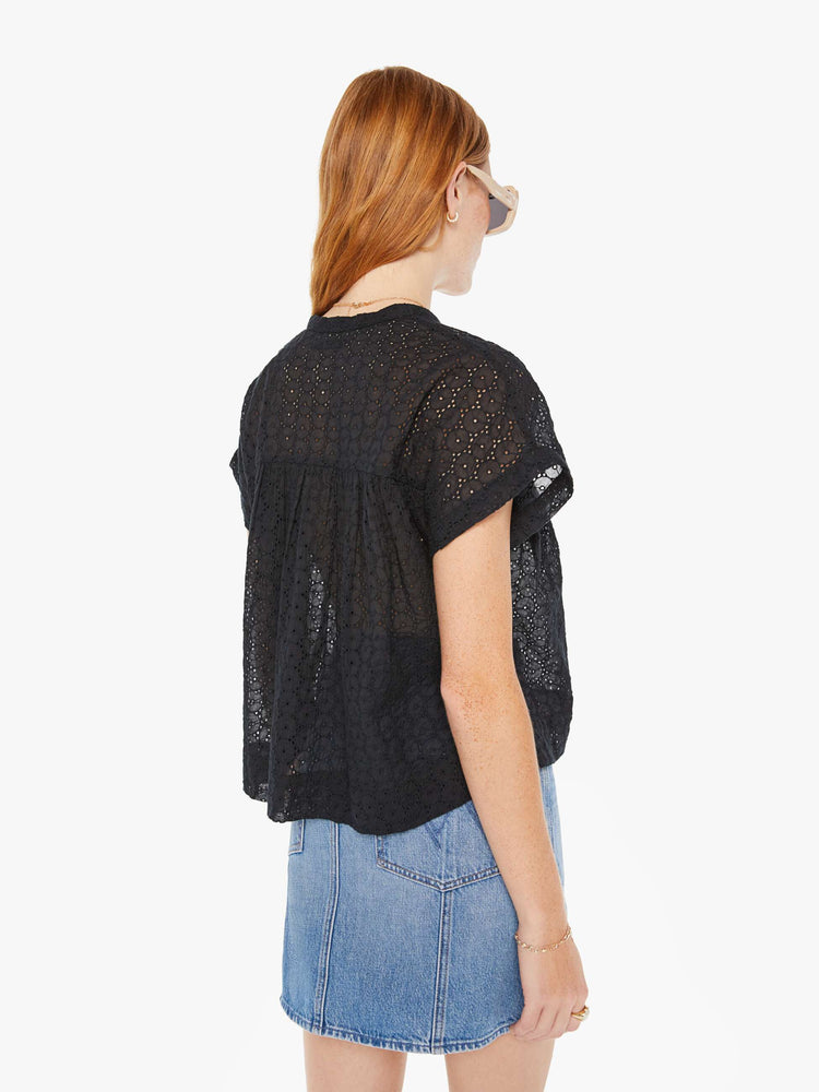 Back view of a woman black lightweight blouse with a buttoned V-neck, short boxy sleeves and ruffles across the chest for a loose, flowy fit.