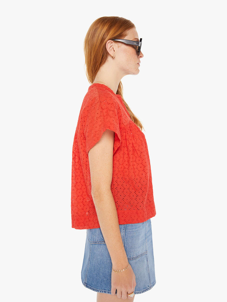 Side view of a woman red lightweight blouse with a buttoned V-neck, short boxy sleeves and ruffles across the chest for a loose, flowy fit.