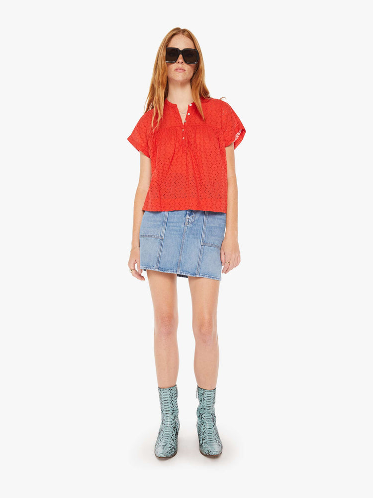 Full body view of a woman red lightweight blouse with a buttoned V-neck, short boxy sleeves and ruffles across the chest for a loose, flowy fit.