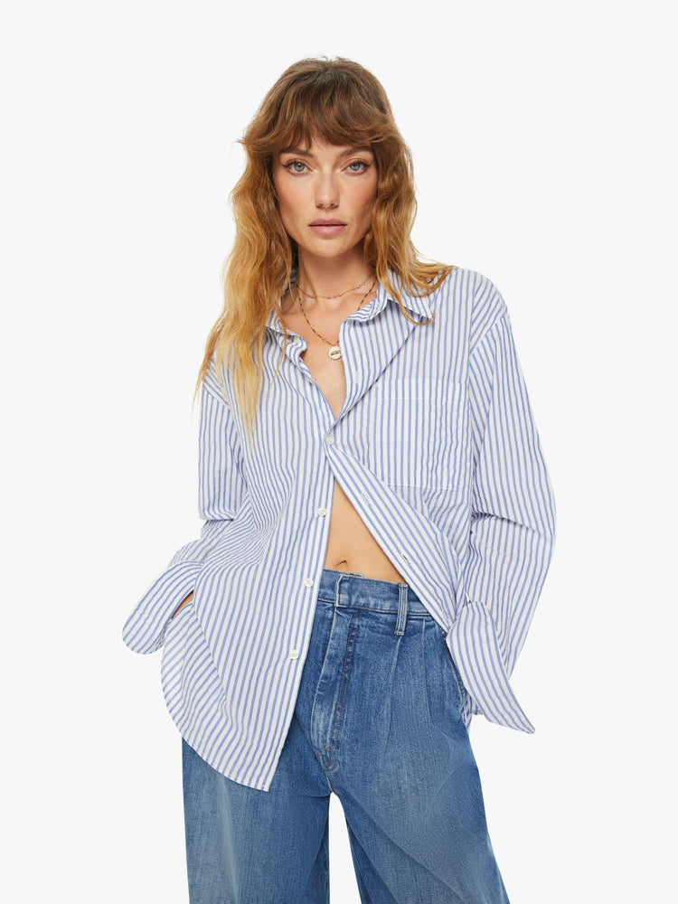 Front view of a woman  oversized button-up is designed with long sleeves, drop shoulders, oversized patch pockets, and a curved hem.