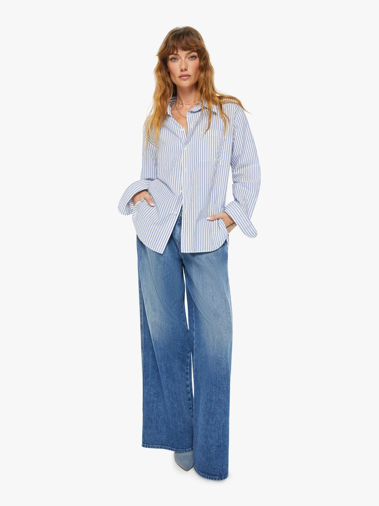 Full body view of a woman oversized button-up is designed with long sleeves, drop shoulders, oversized patch pockets, and a curved hem.