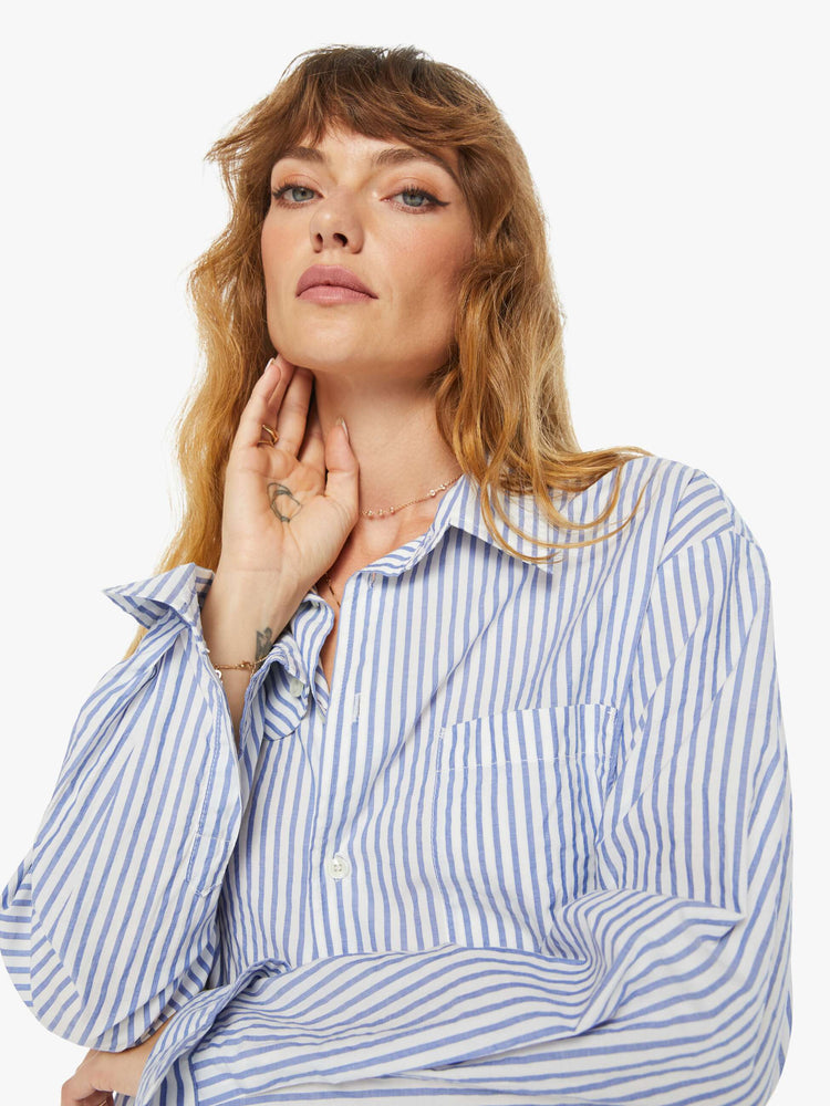 Close up view of a woman oversized button-up is designed with long sleeves, drop shoulders, oversized patch pockets, and a curved hem.