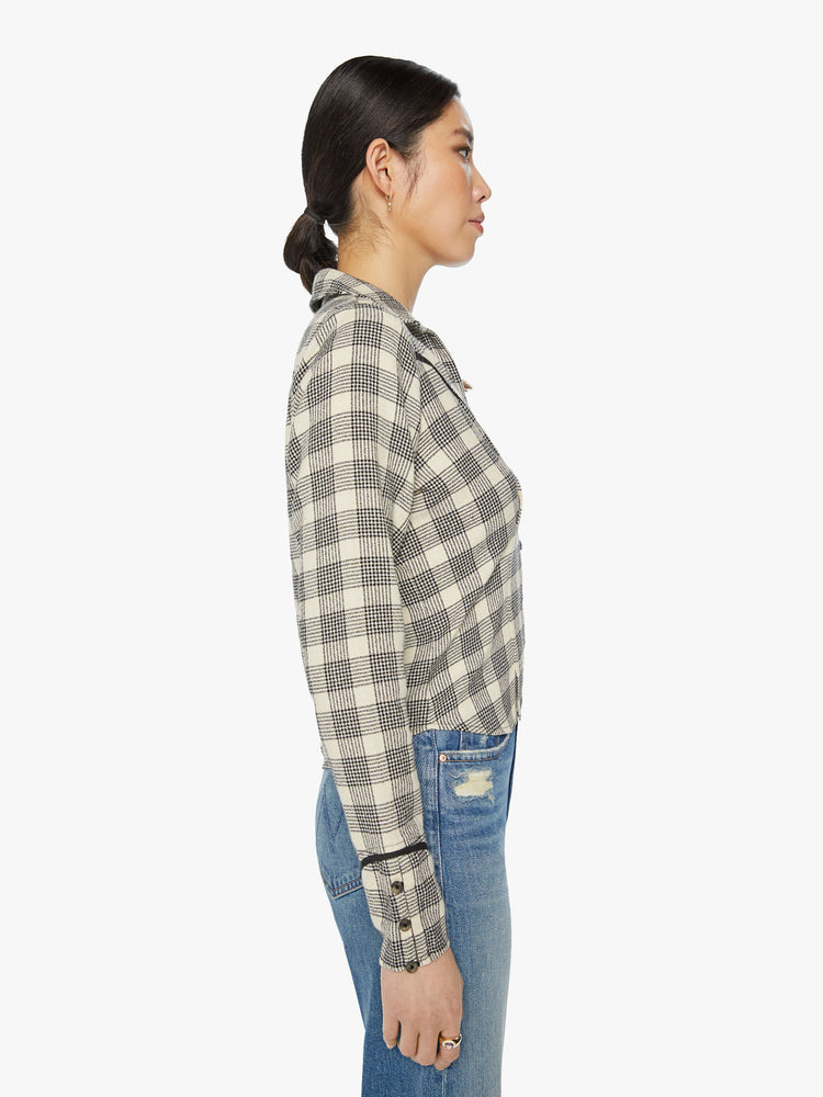 Side view of a woman western inspired button-up with a V-neck, yolk detailing, buttons at the wrists and a slightly cropped hem in black and white plaid print.