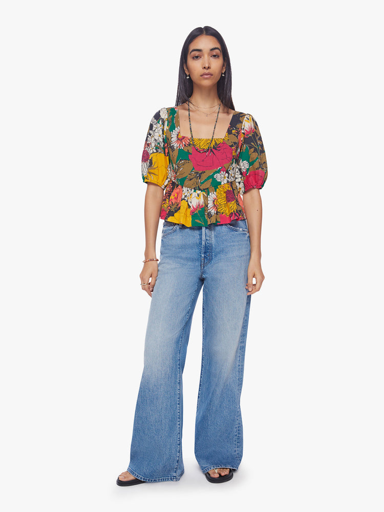 Full body view of woman square-neck blouse with elbow-length balloon sleeves and a ruffled peplum hem in an oversized floral print.