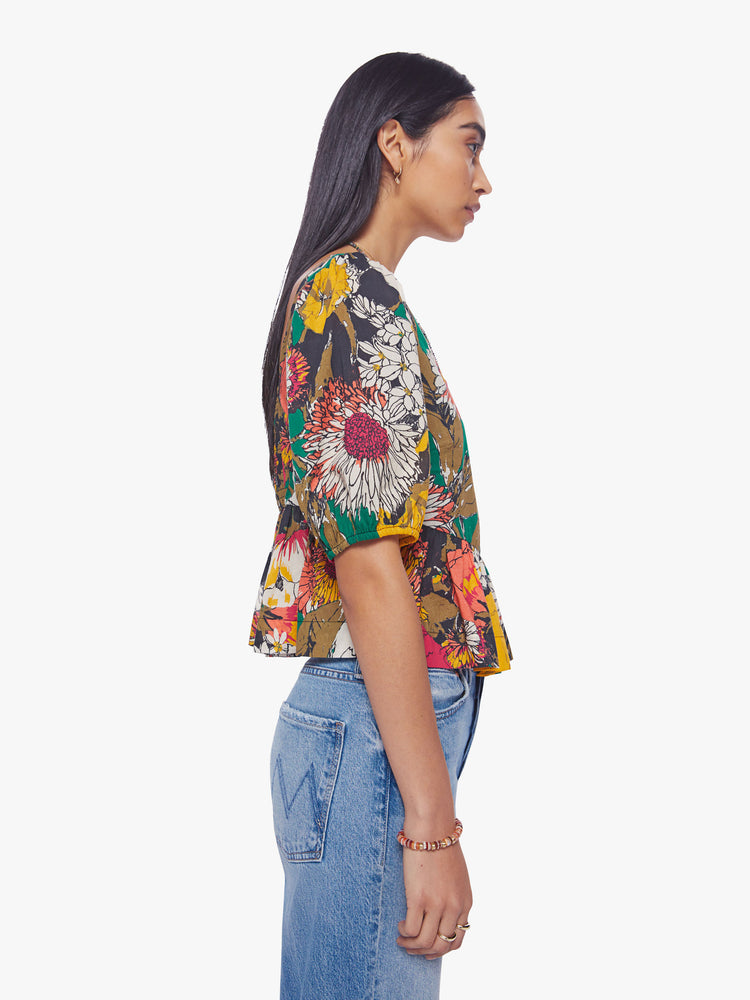 Side view of woman square-neck blouse with elbow-length balloon sleeves and a ruffled peplum hem in an oversized floral print.
