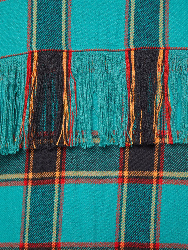 Swatch view of a woman western inspired button-up with drop shoulders, a curved hem and fringe across the chest and back in a bright blue, red and yellow plaid paint.