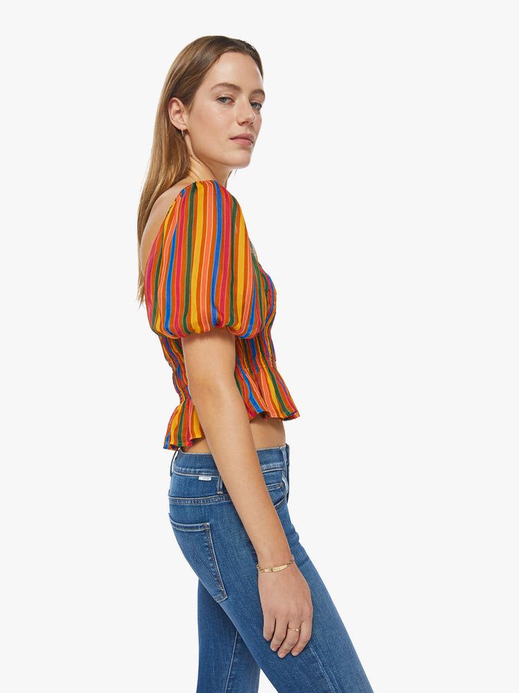 Side view of a womens top featuring a multi color stripe print, a square neckline, balloon short sleeves, and a smocked bodice.