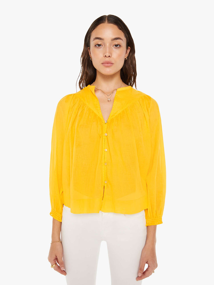Front view of a woman bright yellow lightweight blouse with a buttoned V-neck, 3/4-sleeves, a slightly cropped hem and ruffles across the chest.