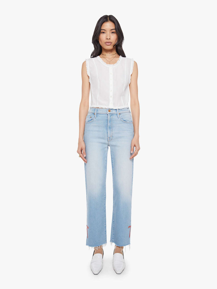 Full body view of woman in a sheer white sleeveless scoop neck blouse with ruffled hems, seamed details, buttons down the front and a cropped fit.