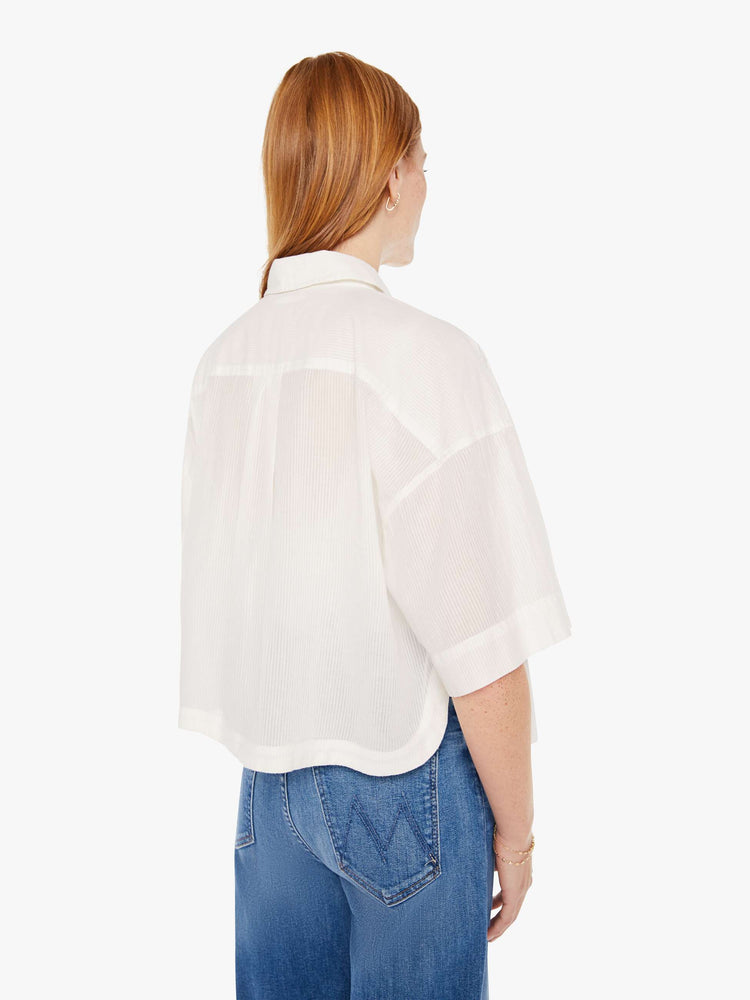 Back view of a womens white button down shirt in a slightly sheer fabric, featuring a cropped boxy fit.