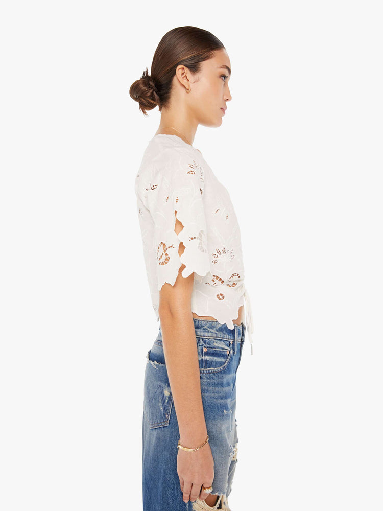 Side view of a womens white blouse featuring eyelet and embroidery details and a cinched center.
