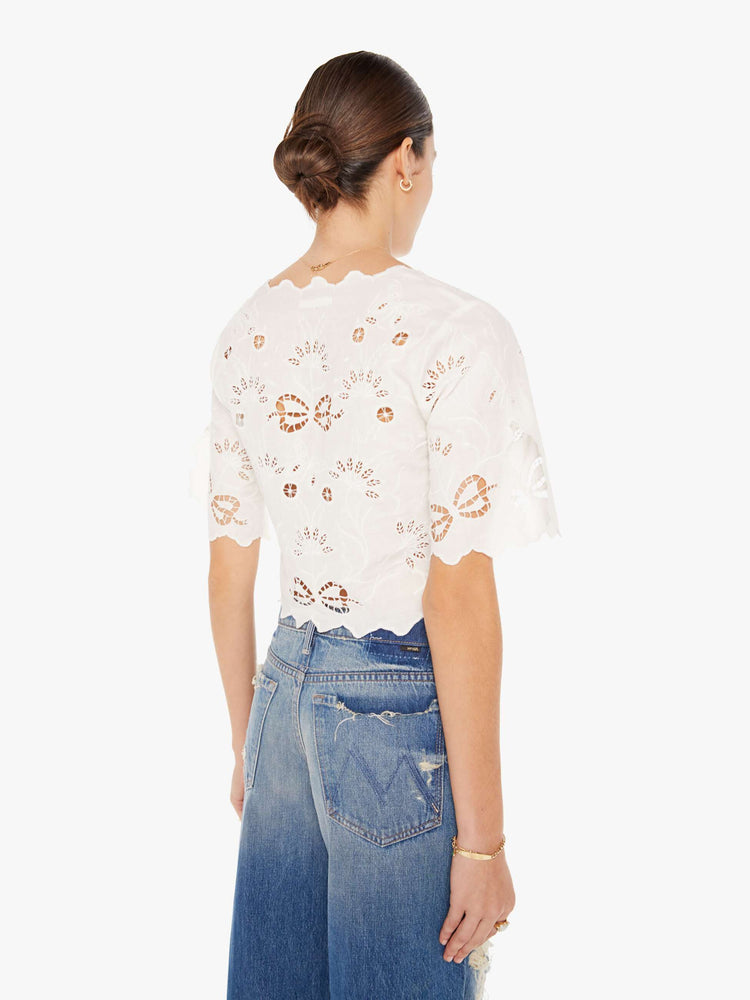 Back view of a womens white blouse featuring eyelet and embroidery details and a cinched center.