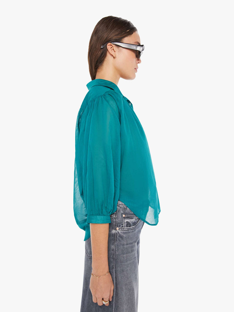 Side view of a womens blouse in a teal green featuring a button down collar and 3/4 length sleeves.