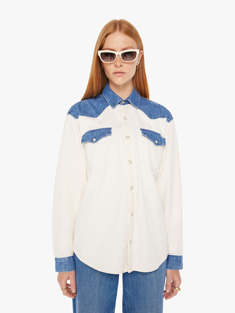 Front view of a womens white button down western denim shirt featuring contrast blue details and snap buttons.