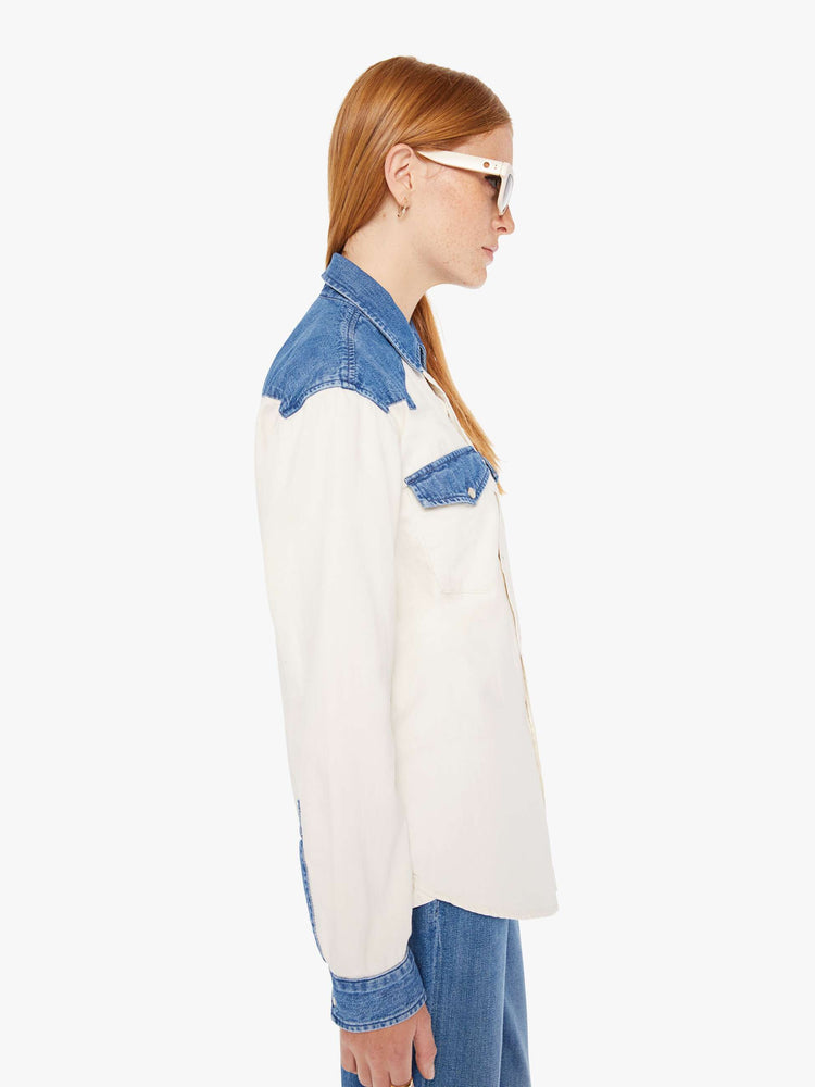 Side view of a womens white button down western denim shirt featuring contrast blue details and snap buttons.