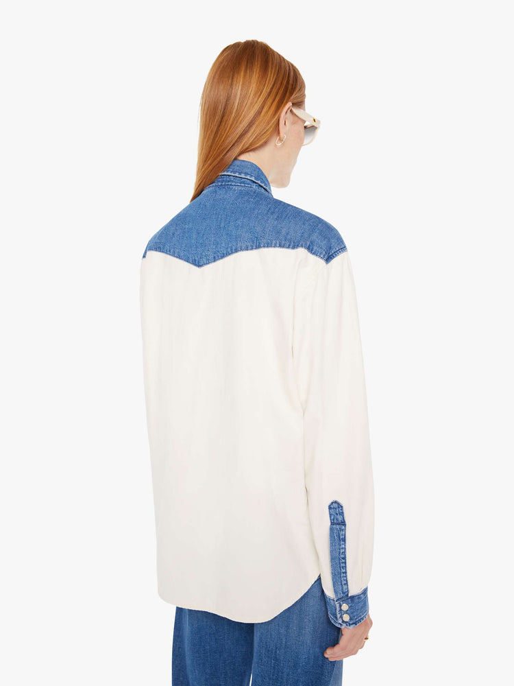 Back view of a womens white button down western denim shirt featuring contrast blue details and snap buttons.