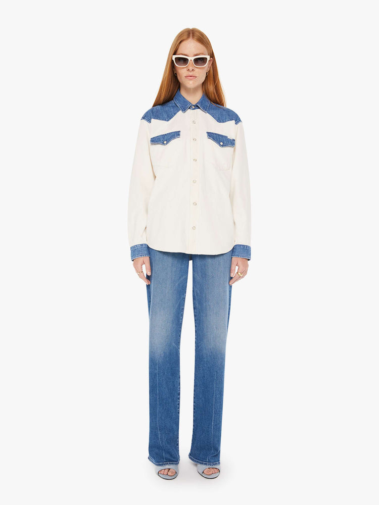 Front full body view of a womens white button down western denim shirt featuring contrast blue details and snap buttons.