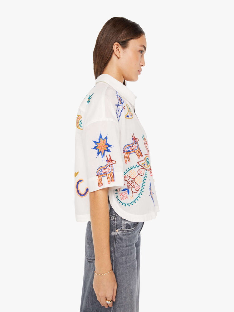 Side view of a womens white button down shirt featuring short sleeves and embroidery throughout.