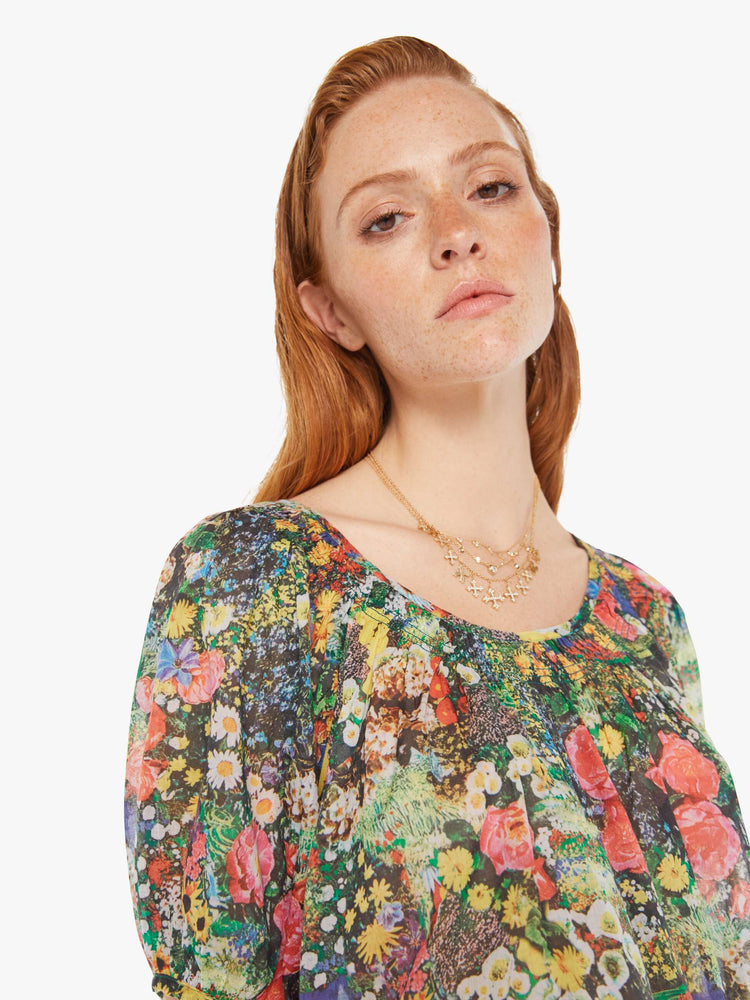 Front close up view of a woman wearing a sheer peasant blouse featuring a colorful garden print.