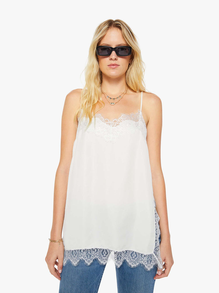 Front view of a woman in a slip top with thin spaghetti straps, a V-neck, side slits, an extra-long hem and a boxy fit.