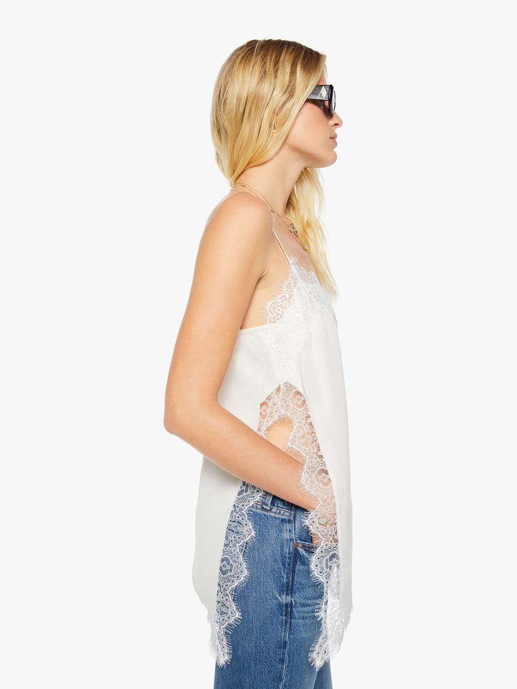Side  view of a woman in a slip top with thin spaghetti straps, a V-neck, side slits, an extra-long hem and a boxy fit.