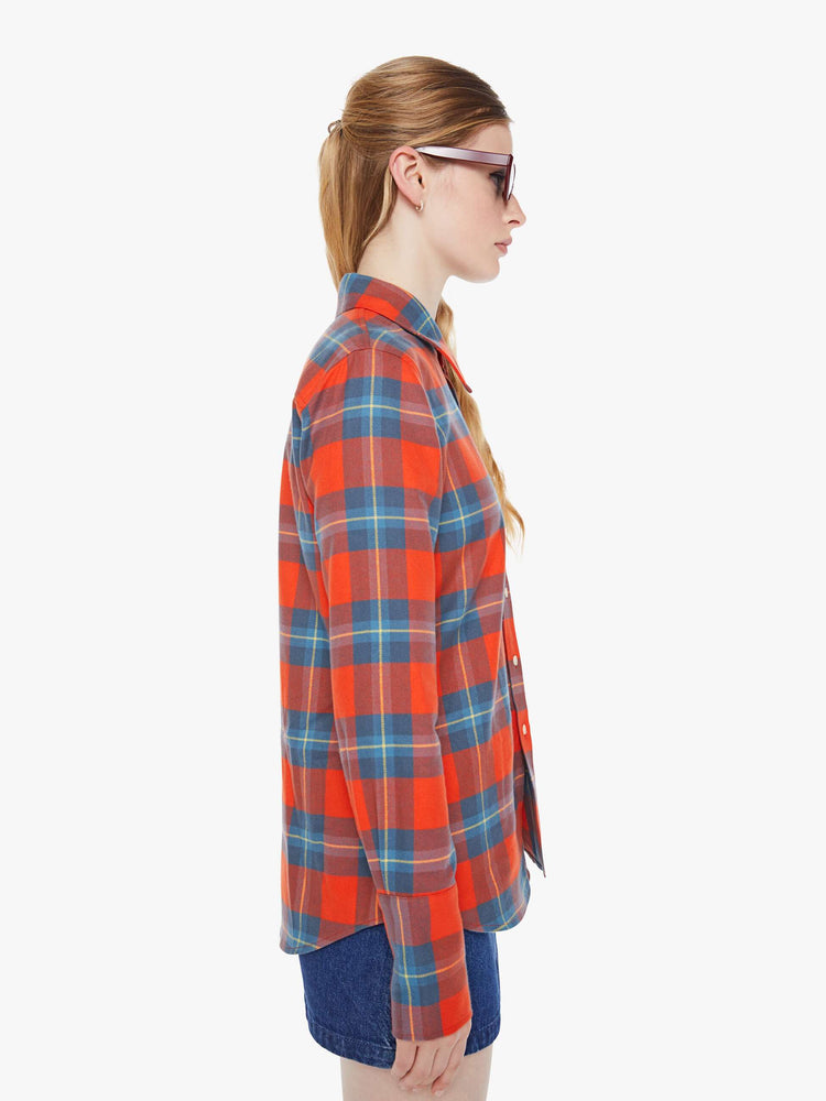 Side view of a woman in a orange and blue plaid print button-up with a pointed collar, long balloon sleeves, extra-wide cuffs at the wrists.