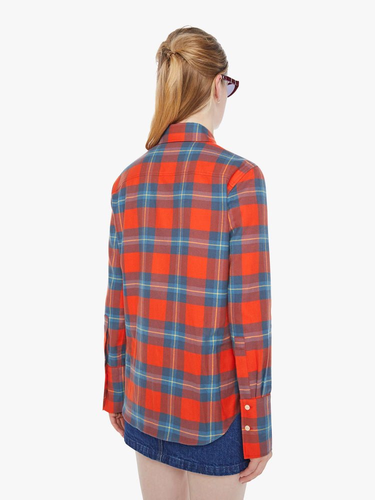 Back view of a woman in a orange and blue plaid print button-up with a pointed collar, long balloon sleeves, extra-wide cuffs at the wrists.