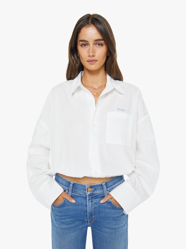 Front view of woman in a white cropped button-up with long wide sleeves and a bubble hem.