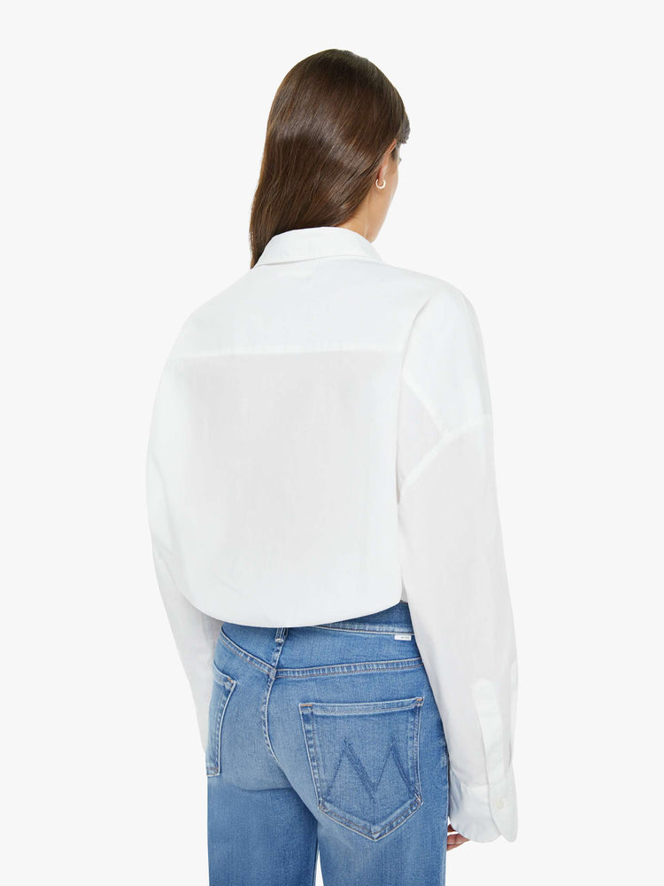 Back view of woman in a white cropped button-up with long wide sleeves and a bubble hem.