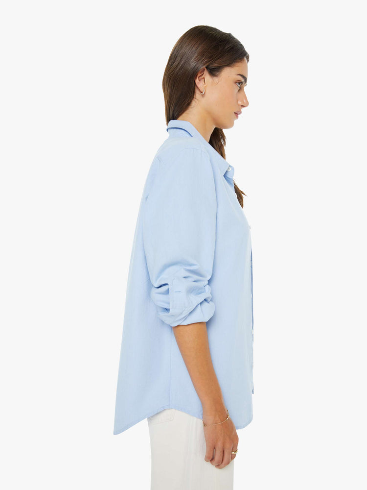 Side view of  woman in a light blue classic button-up with a curved hem and MOTHER's name embroidered on the chest.